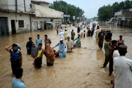 Người di dời lội qua một khu vực ngập nước ở thành phố Peshawar, tỉnh Khyber Pakhtunkhwa (Pakistan) ngày 27-7. Ảnh: CNN