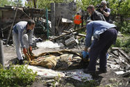 Cảnh sát và người dân Ukraine đang sơ tán thi thể của một dân thường thiệt mạng trong đợt pháo kích của Nga tại làng Malaya Rohan, ngoại ô Kharkiv, ngày 16-5.