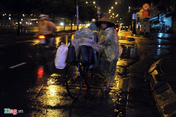 Một người phụ nữ dắt xe dưới trời mưa trên đường Võ Văn Kiệt (quận 6).