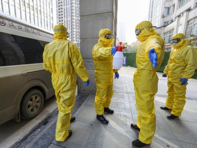 Nhân viên y tế mặc quần áo bảo hộ và khử trùng phòng nhiễm virus Corona. Ảnh: AP