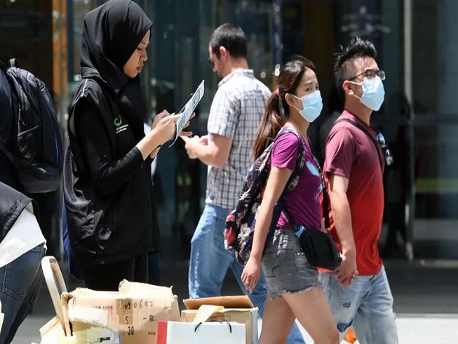 Một tình nguyên viên của Bộ Truyền thông Singapore thu thập phản hồi của người dân về tình hình dịch Corona. Ảnh: AFP