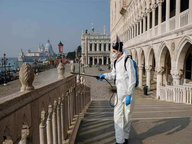 Nhân viên y tế khử trùng tại cầu Ponte della Paglia trên quảng trường Saint Mark ở TP Venice, Ý. Ảnh: REUTERS