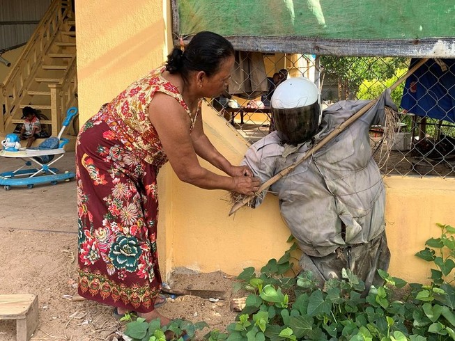 Bà Ek Chan đang chỉnh trang lại cho một bù nhìn Ting Mong trước nhà. Ảnh: REUTERS