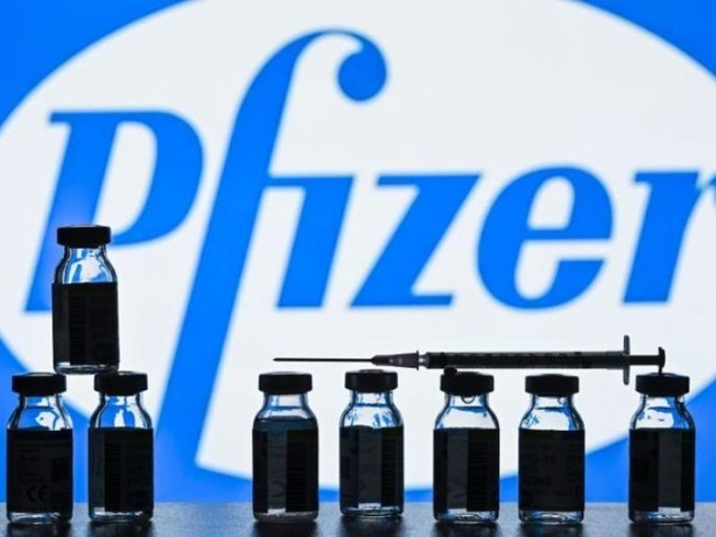 Những lọ vaccine ngừa COVID-19 xếp trước logo tập đoàn dược phẩm Mỹ Pfizer.