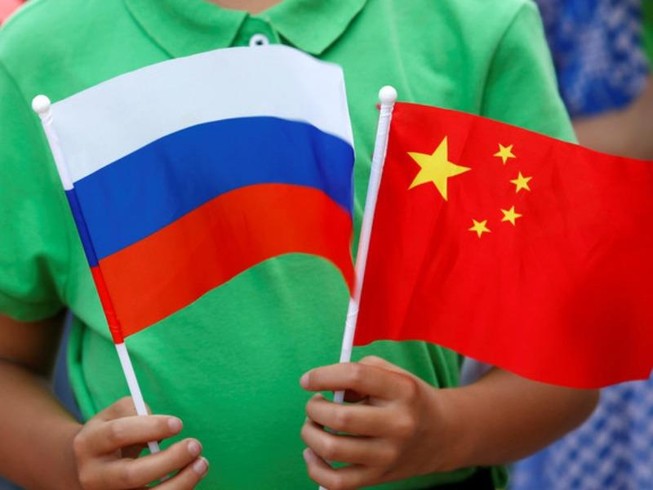 Một đứa trẻ cầm quốc kỳ của Nga và Trung Quốc tại lễ đón Tổng thống Nga Vladimir Putin đến thăm Bắc Kinh, ngày 25-6-2016.