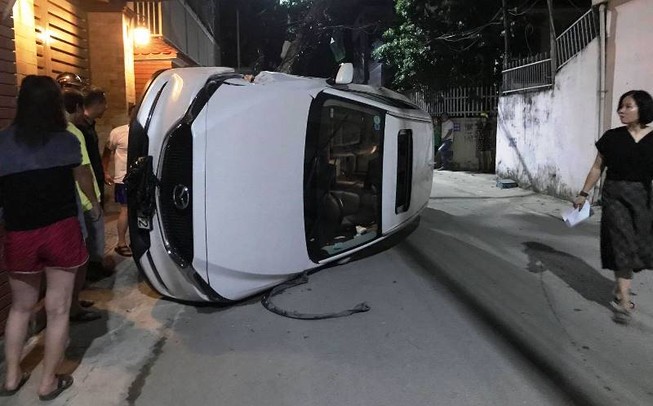 Xe hơi đâm gãy cột điện rồi lật nghiêng giữa đường