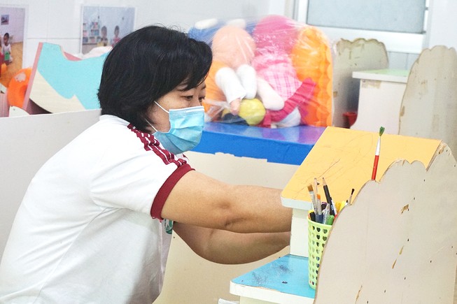 Giáo viên Trường Mầm non Hạnh Thông Tây, quận Gò Vấp vệ sinh trường lớp để đón trẻ đi học lại. Ảnh: NGUYỄN QUYÊN