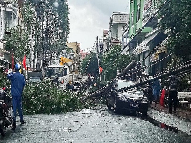 Cột điện gãy đè lên xe biển xanh đang đậu trên đường