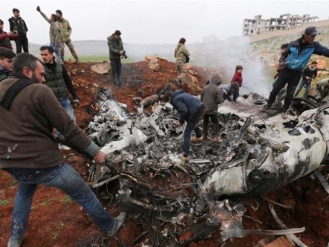 Người dân tập trung quanh mảnh vỡ chiếc trực thăng của chính phủ Syria bị bắn rơi ở tây Aleppo, Syria. Ảnh: AP