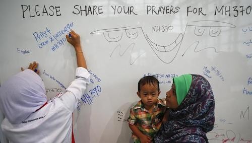 Một phụ nữ viết những lời cầu nguyện cho các nạn nhân bị mất tích. Ảnh: Reuters Một phụ nữ viết những lời cầu nguyện cho các nạn nhân bị mất tích. Ảnh: Reuters